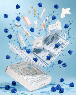 Cosmetic products floating in the air and packaging with blue raspberry and water splashes on a light blue background